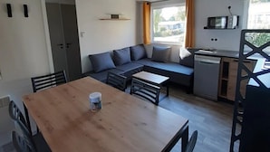 Un espacio habitable moderno y funcional con una mesa de comedor de madera, un sofá y una zona de cocina con microondas.