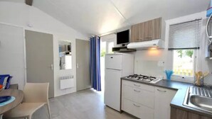 A compact kitchen with a gas stove, white cabinets, and a small dining area with a table and chairs.