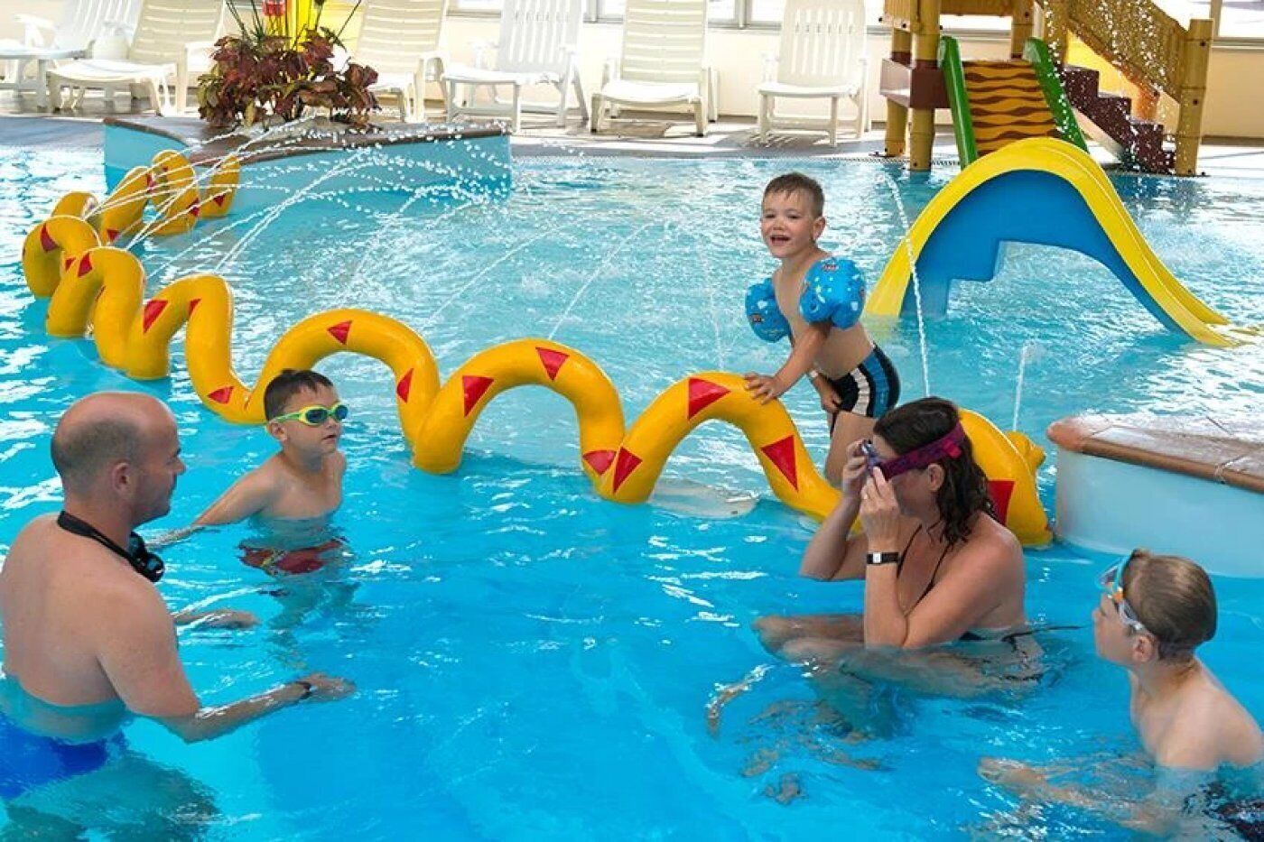 Una piscina con flotadores inflables y un tobogán.