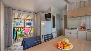 Une cuisine moderne avec un coin repas, un réfrigérateur et une table sur laquelle se trouvent des fruits.