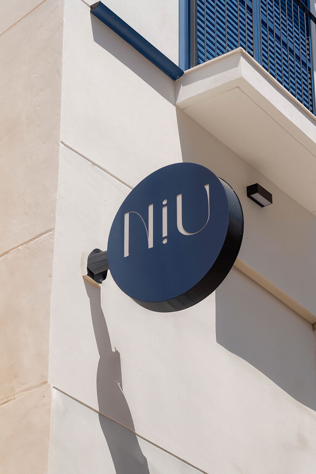 Un edificio con un letrero que dice "niU" sobre un muro blanco.