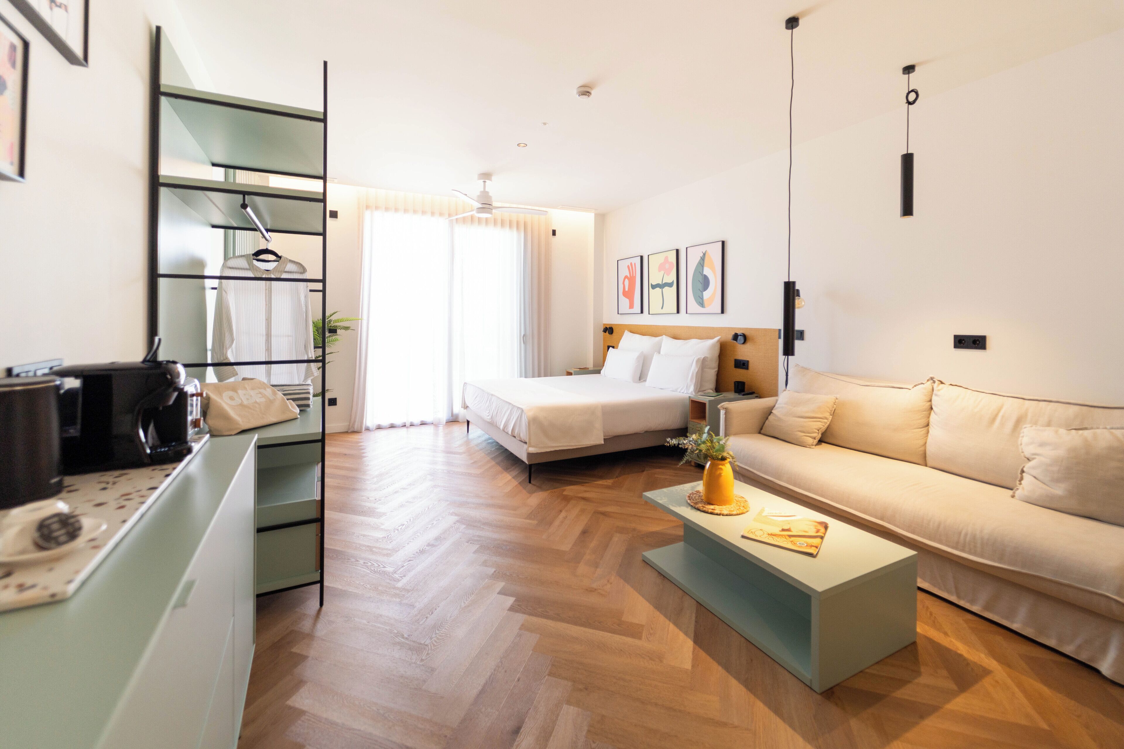 Una habitación de hotel moderna con cama, sofá, mesa de centro y una zona de kitchenette.