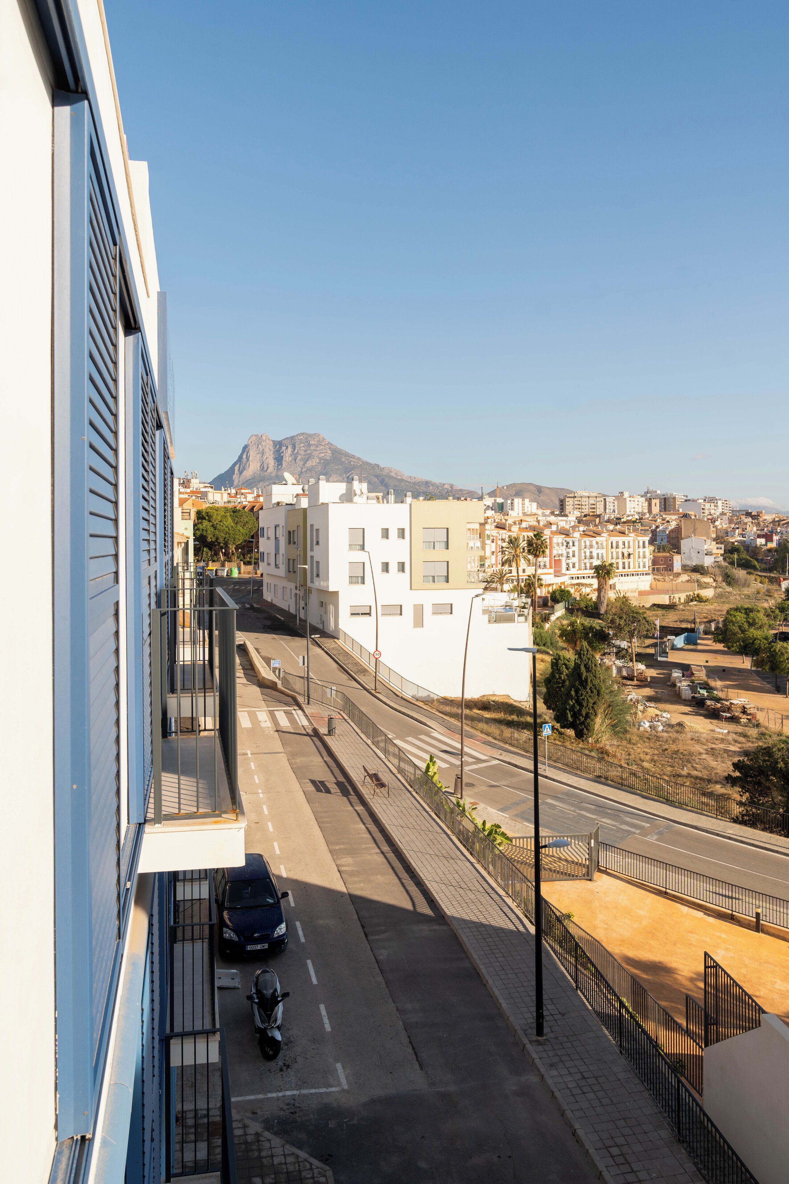 A street view with a clear sky, buildings, and a mountain in the distance.
