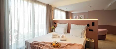 Una camera d'albergo moderna con un letto grande, un comodino con una lampada, una poltrona rosa e un vassoio per la colazione sul letto.