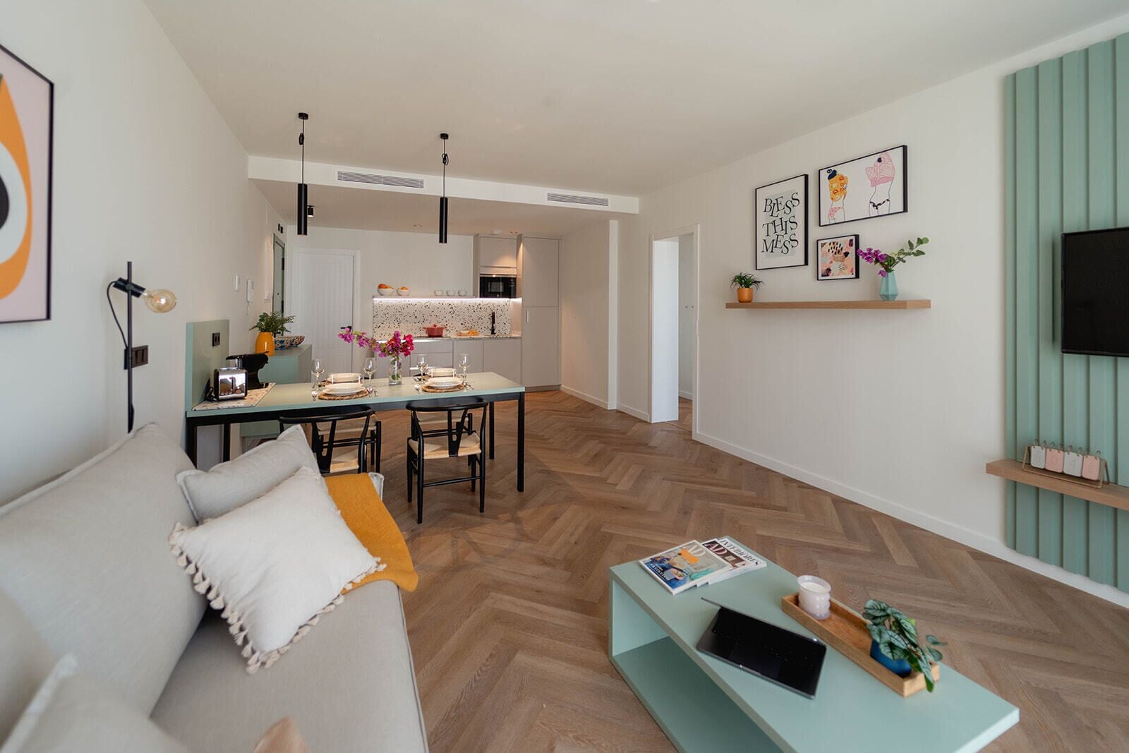 Una sala de estar moderna con sofá, mesa de comedor y cocina al fondo.