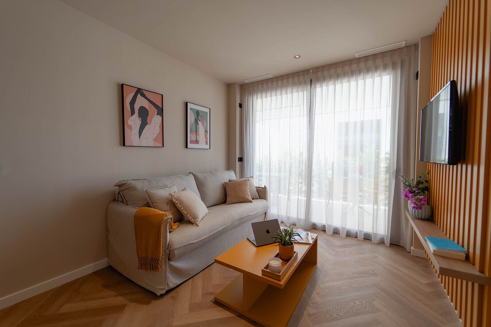 Un salon moderne avec un canapé, une table basse, un ordinateur portable et un téléviseur.