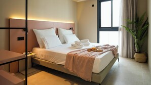 A modern hotel room with a large bed, bedside table, and a potted plant. - NIU Line (Villajoyosa)