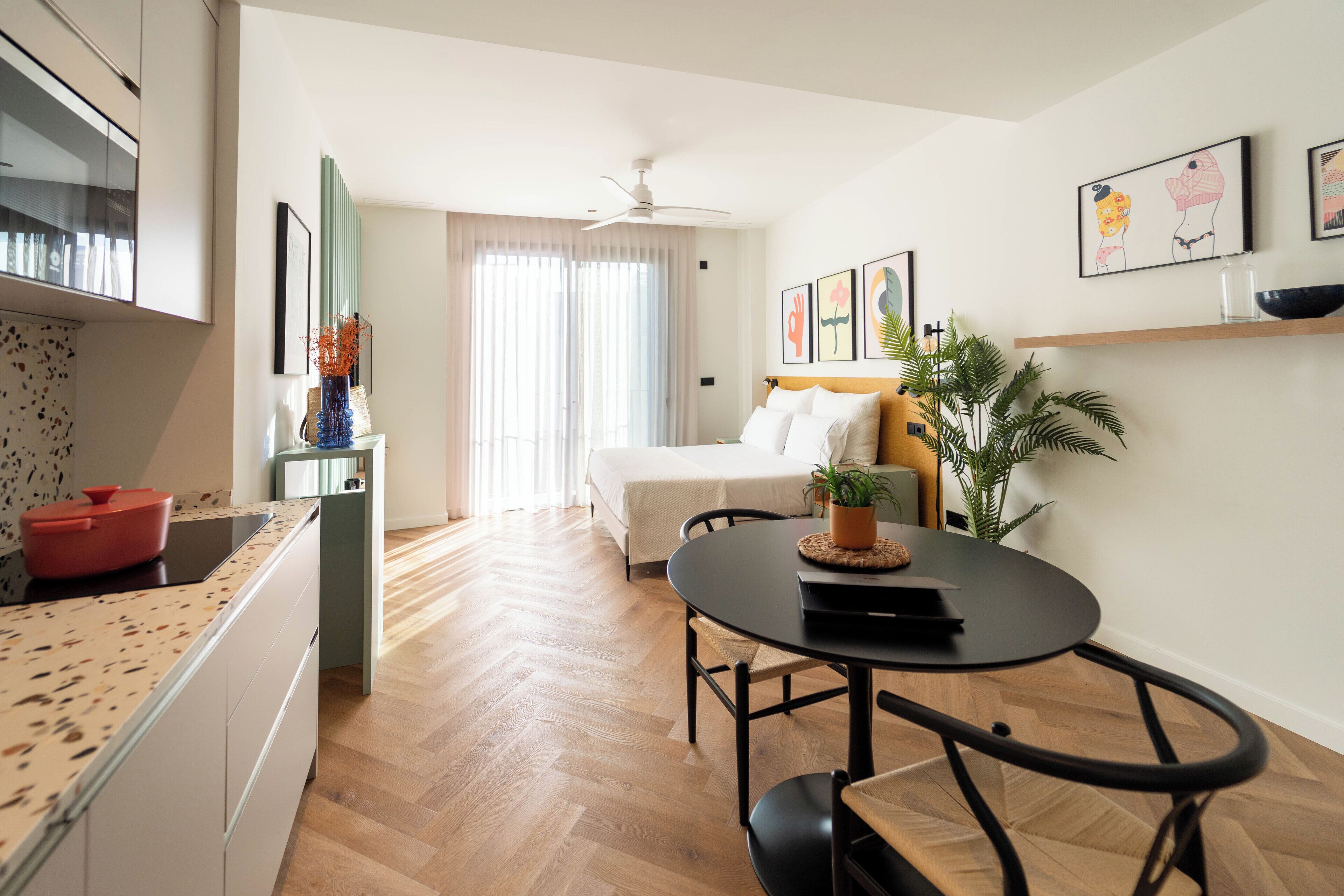Una habitación de hotel moderna con cocina, comedor y cama.