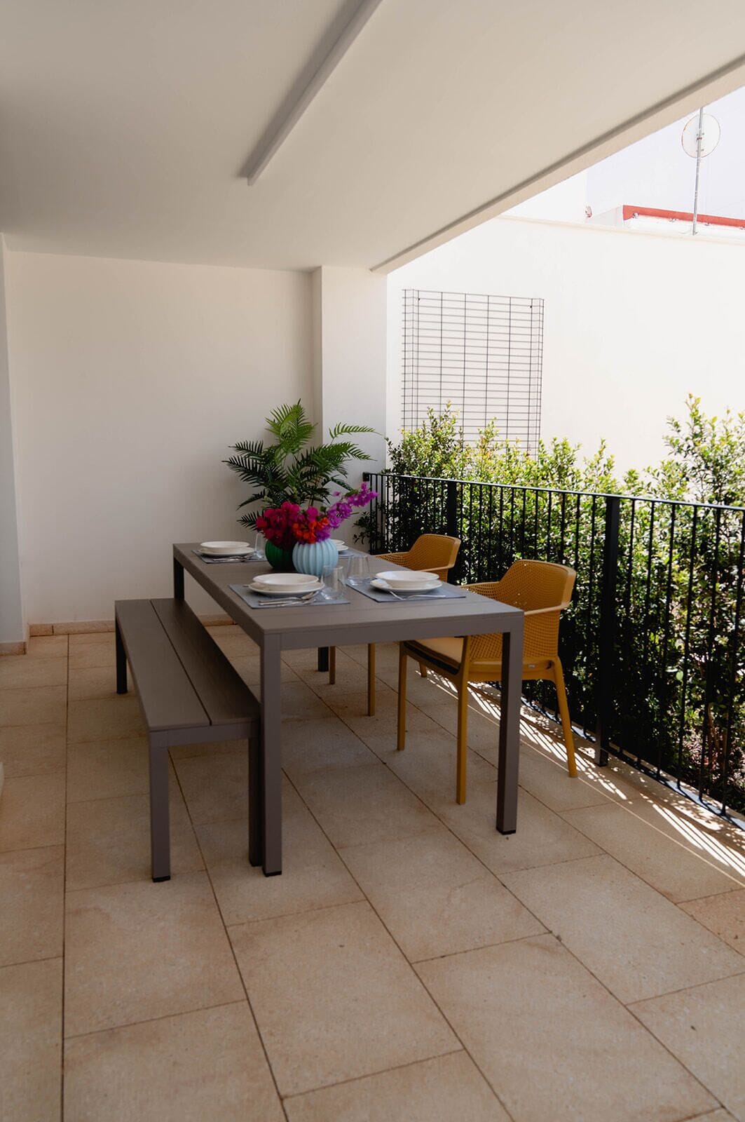 A balcony with a dining table set for two, surrounded by chairs.