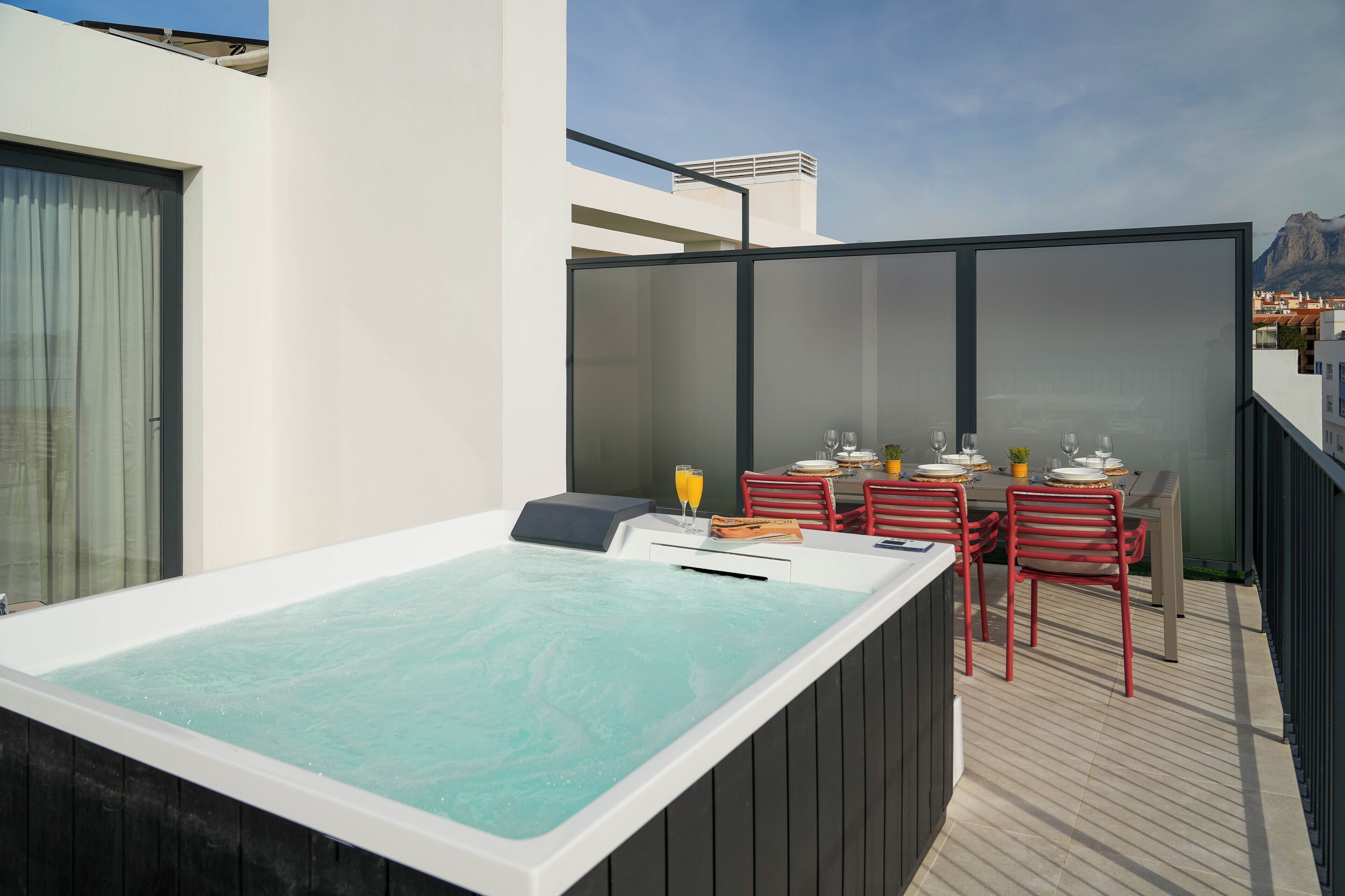A rooftop terrace with a hot tub, outdoor seating, and a view of the city.