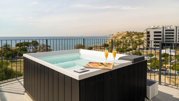A hot tub with a view of the sea, a book, and two glasses of orange juice on a balcony. - NIU Line (Villajoyosa)