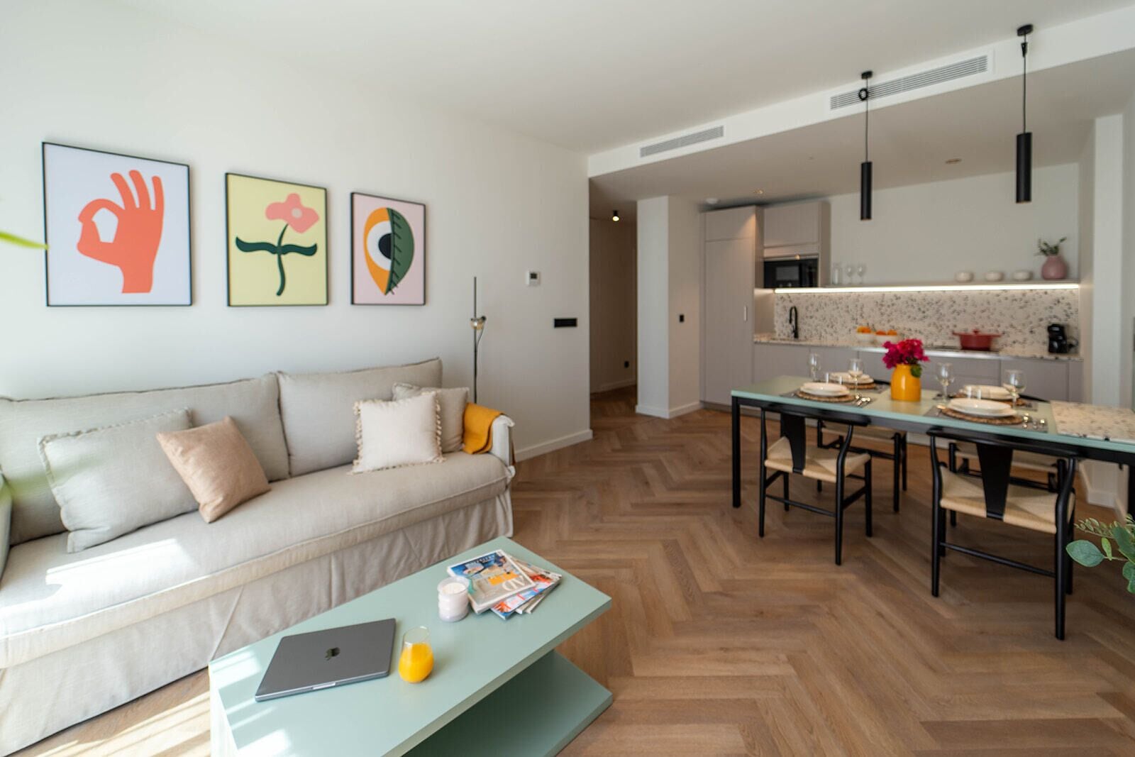 A modern living room with a sofa, coffee table, and a dining area with a table set for four.