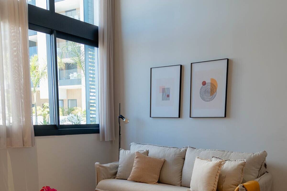 A living room with a sofa, a red coffee table, and two framed artworks on the wall.