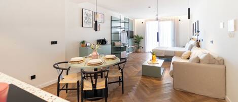 Un salon moderne avec un canapé, une table à manger et des chaises, et un coin cuisine en arrière-plan.