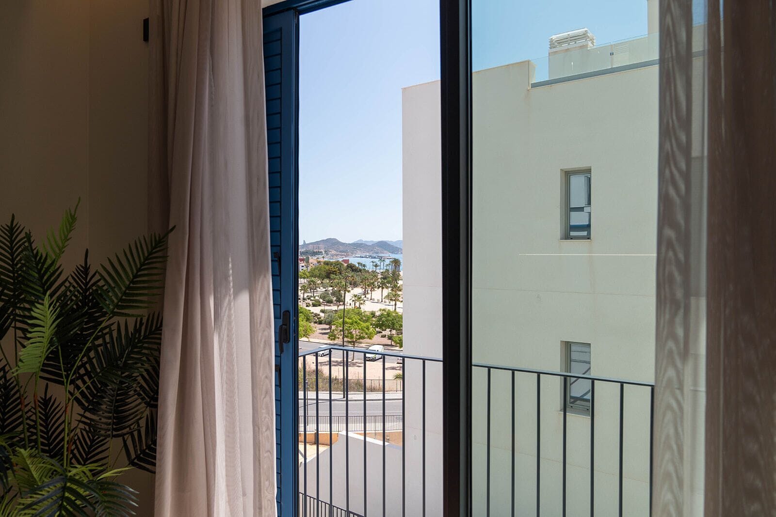 Un balcón con vista a la costa, que incluye edificios y montañas.