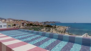 A rooftop infinity pool with a view of the sea and a coastal cityscape. - NIU Line (Villajoyosa)