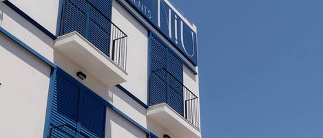 A multi-story building with balconies and a sign that reads "BE LINE APARTMENTS."
