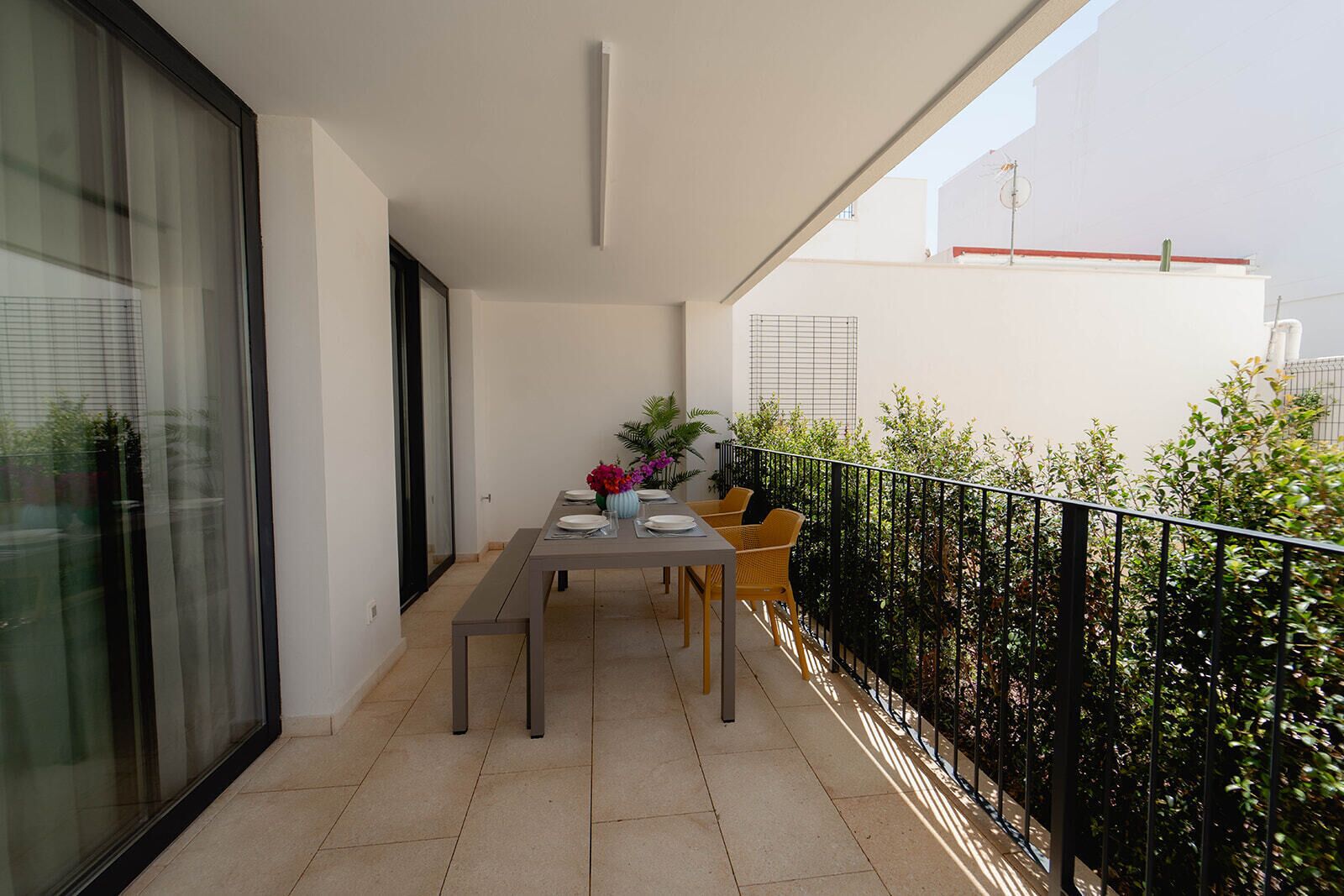 Ein Balkon mit Esstisch, Stühlen und einem Blumenstrauß.