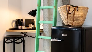 A kitchenette with a coffee maker, a small table, a stool, and a green ladder against a concrete wall. - Espace 43 Les 7 chambres (Namur)