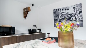 A modern kitchen with a marble countertop, a microwave, a coffee maker, and a vase of flowers. - Espace 43 Les 7 chambres (Namur)