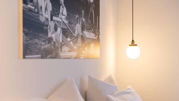 Un dormitorio con una cama, almohadas, una lámpara colgante y una fotografía blanco y negro en la pared.