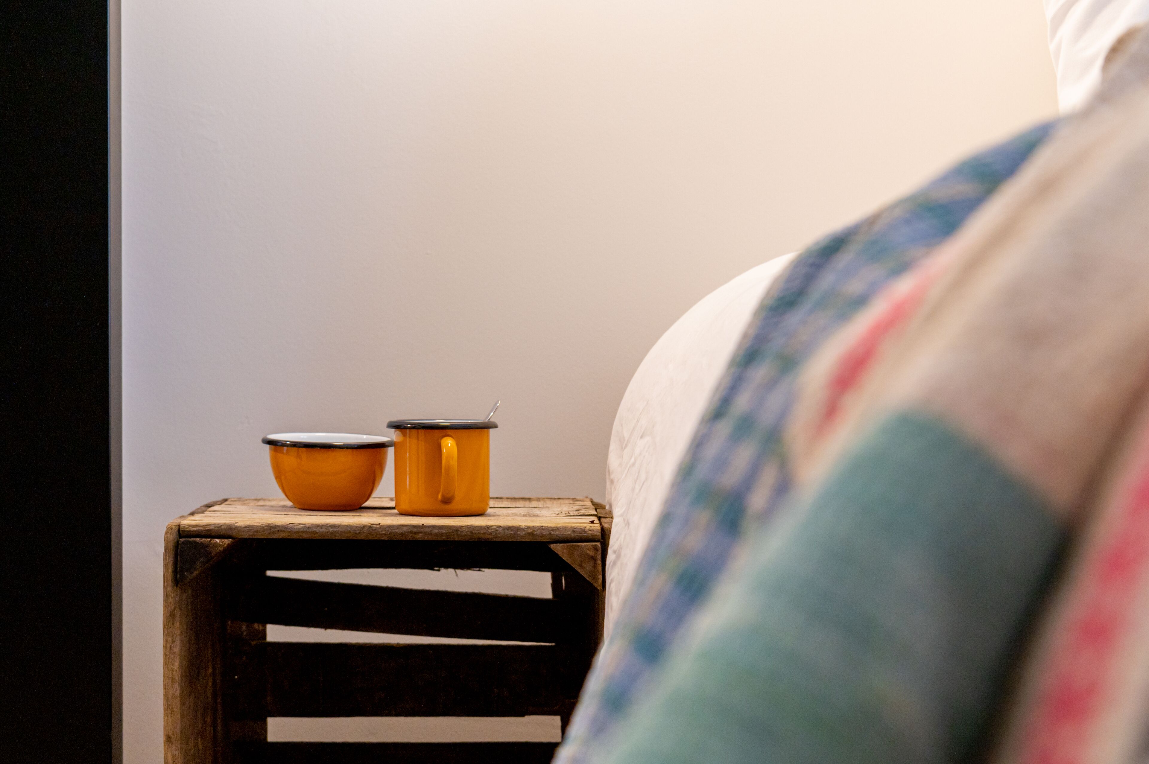 A wooden nightstand with two orange containers and a white wall in the background.