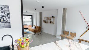 A modern living room with a marble table, a sofa, and a coffee table. There is a wall-mounted shelf with decorative items and a framed picture. - Espace 43 Les 7 chambres (Namur)