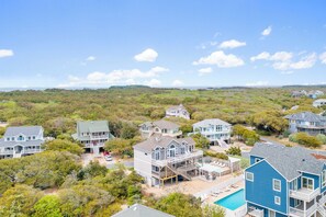 A coastal residential area with multiple houses, including a large house with a pool and a smaller house with a deck.