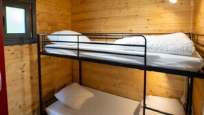 Dormitorio con literas, paredes de madera y techo inclinado.