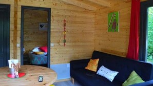 A wooden cabin interior with a sofa, a table with a cup and candy canes, and a door leading to another room.