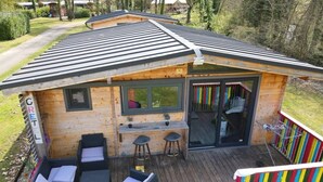 A wooden cabin with a deck, a bar area, and outdoor seating.