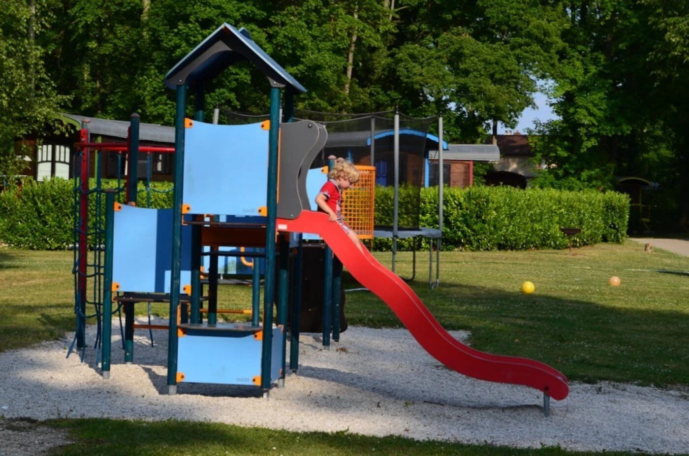 Un'area giochi con uno scivolo rosso e strutture per arrampicarsi.