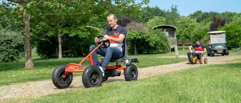 A person riding a red electric lawn mower on a grassy path.