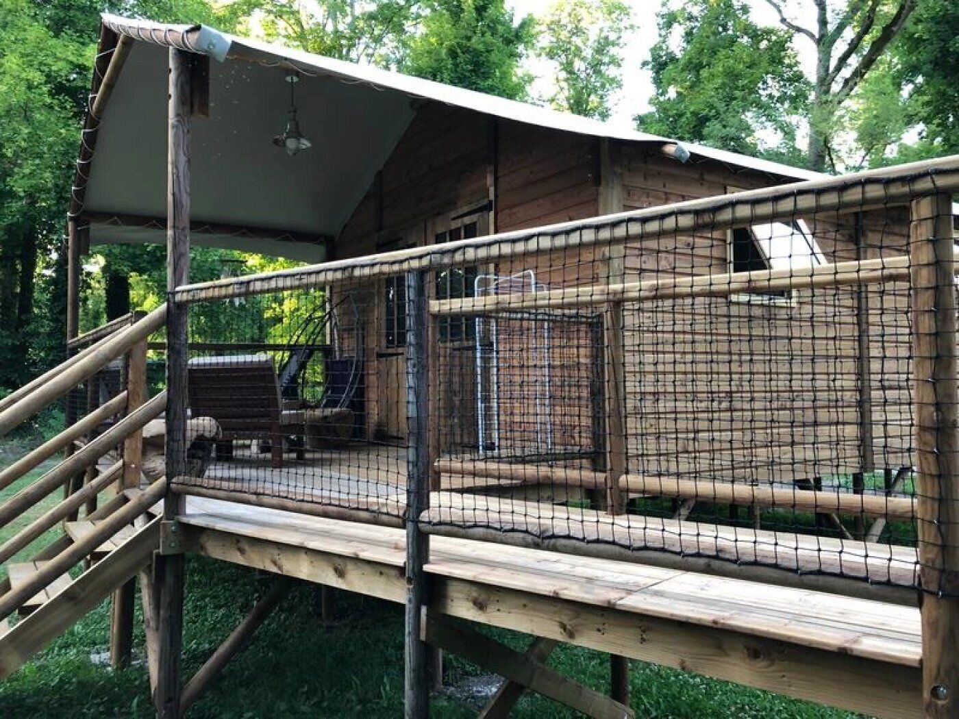 A wooden deck with a netted enclosure, a wooden bench, and a small table.
