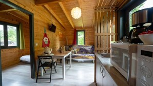 Un intérieur de chalet chaleureux, avec un revêtement en bois, un coin repas, un canapé et une petite cuisine.