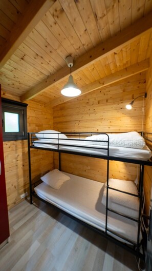 Ein Schlafraum mit Etagenbetten, Holzwänden und einer geneigten Decke.