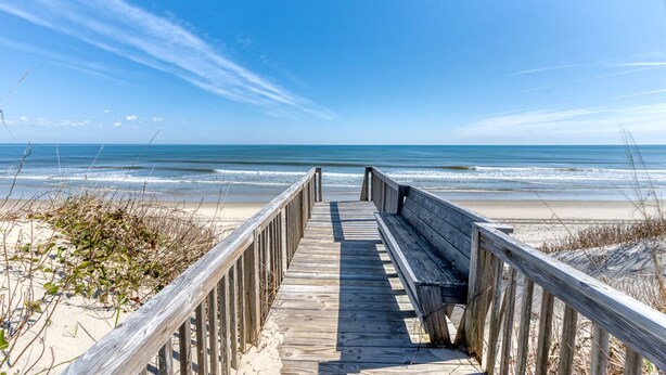 A wooden boardwalk leading to a beach with clear skies. - The beautiful beaches of Corolla are just a few feet away at Oasis! (Corolla)