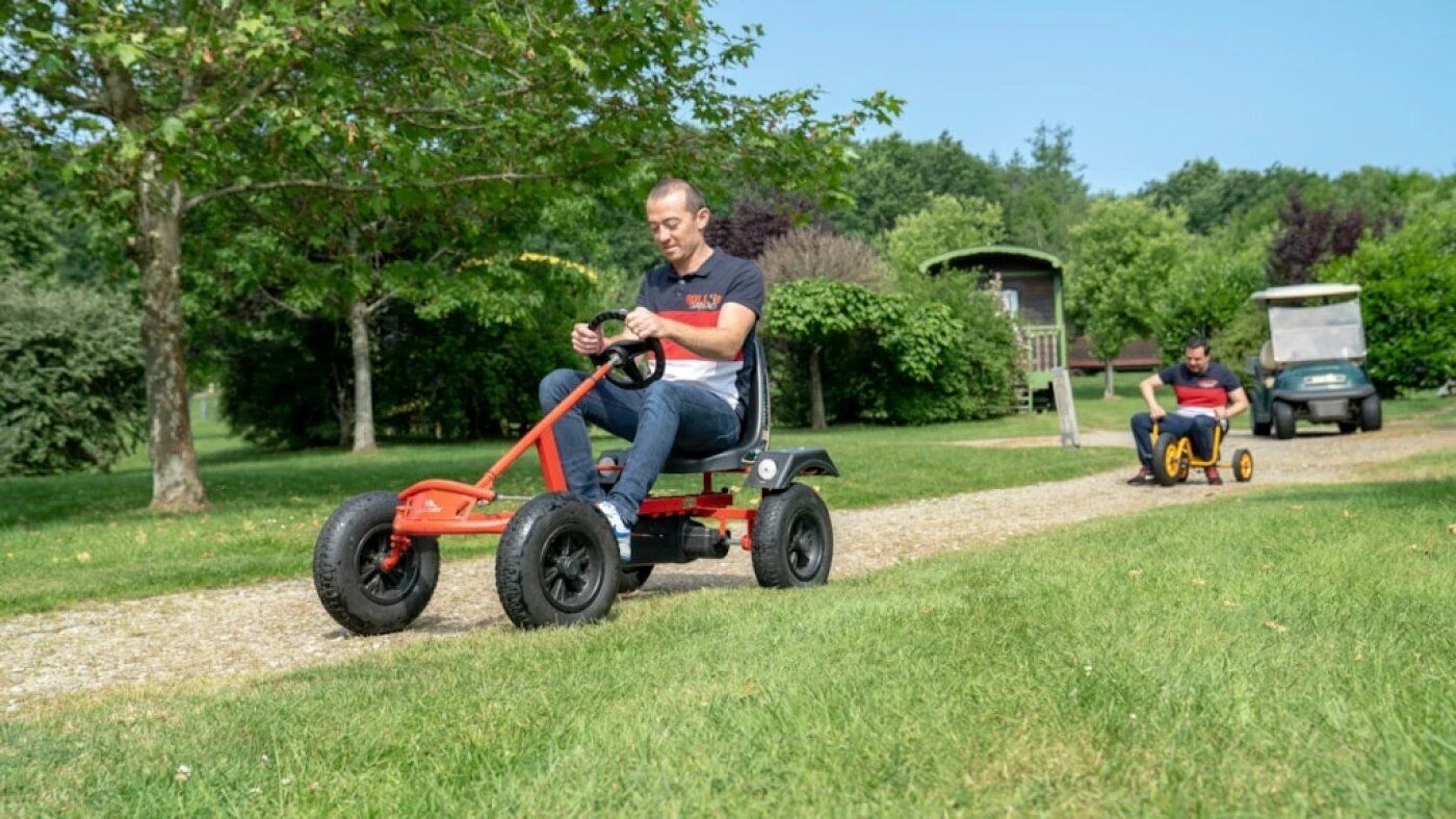 A person riding a red electric lawn mower on a grassy path.