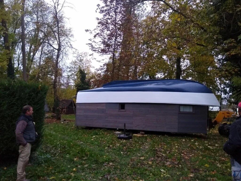 A small, single-story building with a flat roof, surrounded by trees and grass.