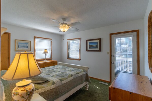 Cozy retreat with a single bed, nightstand, and lamp, plus a ceiling fan and framed artwork.