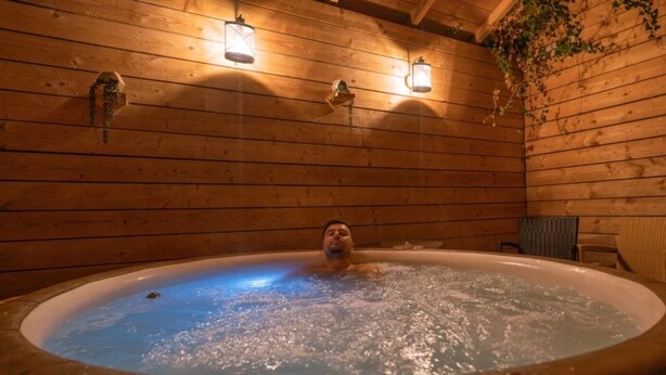 A wooden cabin interior with a hot tub, wooden walls, and hanging lanterns. - ZEcamping 2 étoiles piscine couverte dog friendly sauna locatif 18m2 5 pers (Bar-sur-Aube)