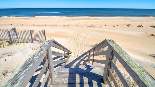 A wooden staircase leading to a sandy beach with a clear view of the ocean. - Sun Realty ocean and sound views only 600 ft from semi-private beach access (Nags Head)