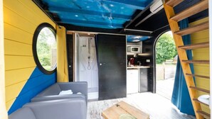 A compact, modern RV interior with a kitchenette, a small seating area, and a shower. - ZEcamping 2 étoiles piscine couverte locatif clim 9m2 (Bar-sur-Aube)