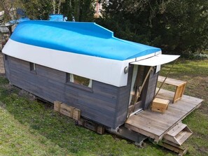 Une petite cabane à un seul étage, avec un toit bleu et une terrasse en bois.