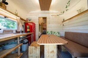 Une cuisine de taille réduite avec une table en bois, un réfrigérateur rouge et un banc.