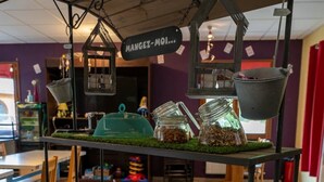 A food cart with various snacks and a sign that reads "Mangez-Moi...". - ZEcamping 2 étoiles piscine couverte sauna locatif 19m2 5 pers (Bar-sur-Aube)