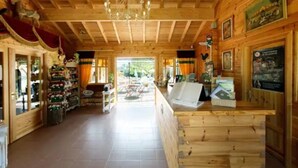 Un intérieur en bois avec un comptoir d’accueil, un sol carrelé et une vue sur l’extérieur.