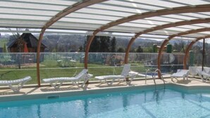 Une piscine avec des chaises longues blanches et un espace abrité.