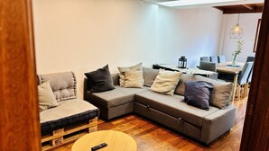 A modern living room with a sectional sofa, a small round coffee table, and a dining area with a wooden table and chairs.