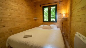 Une pièce de cabane en bois comprenant un lit, une fenêtre et une lampe fixée au mur.